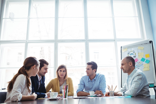 Group of people in a meeting sitting around a table talking.