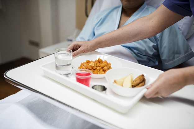 Someone serving a meal to a patient at the hospital