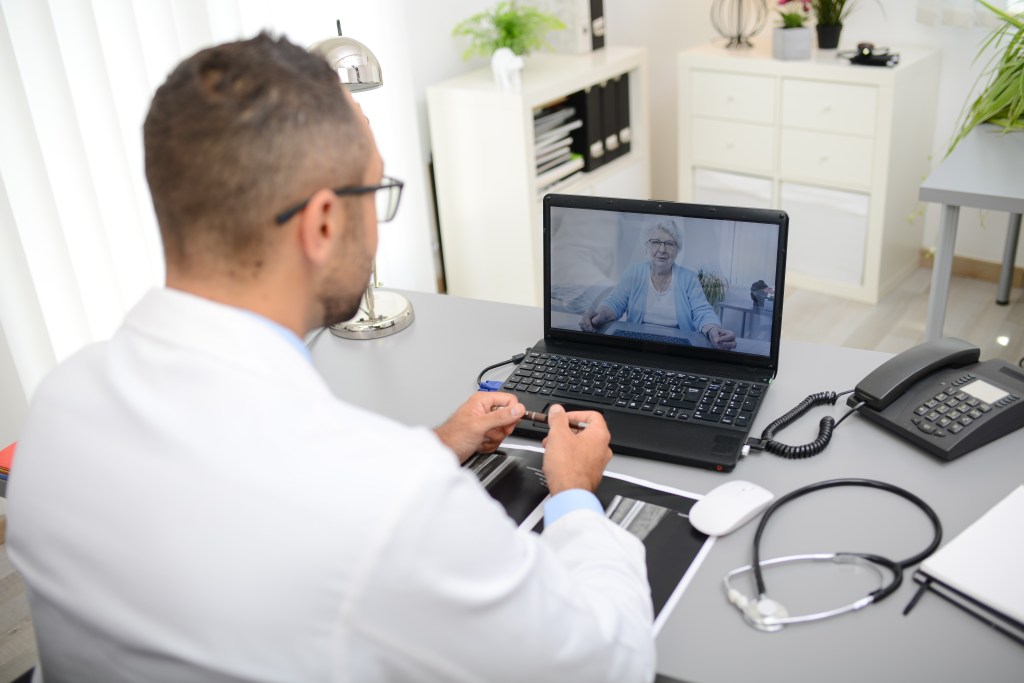 doctor giving a remote medical consultation with senior woman patient over internet computer telemedecine diagnostic